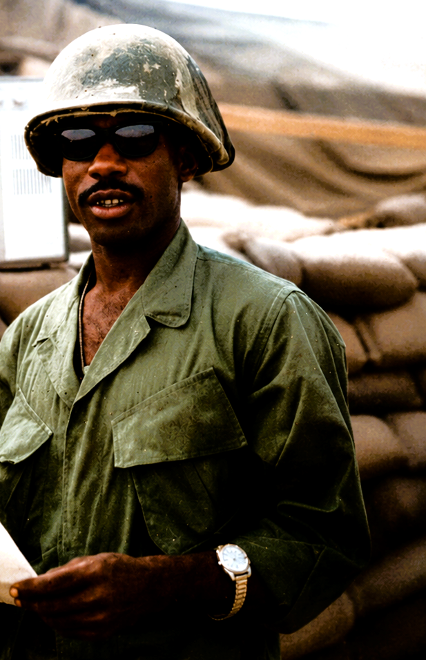 Leon Collier wearing a bush hat beside a sandbag bunker.